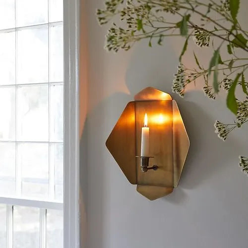 brass wall sconce with lit candle 