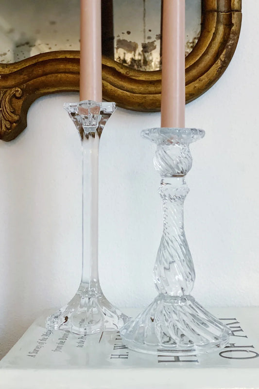 pair of glass candle stick holders with floral society taper candles and antique mirror