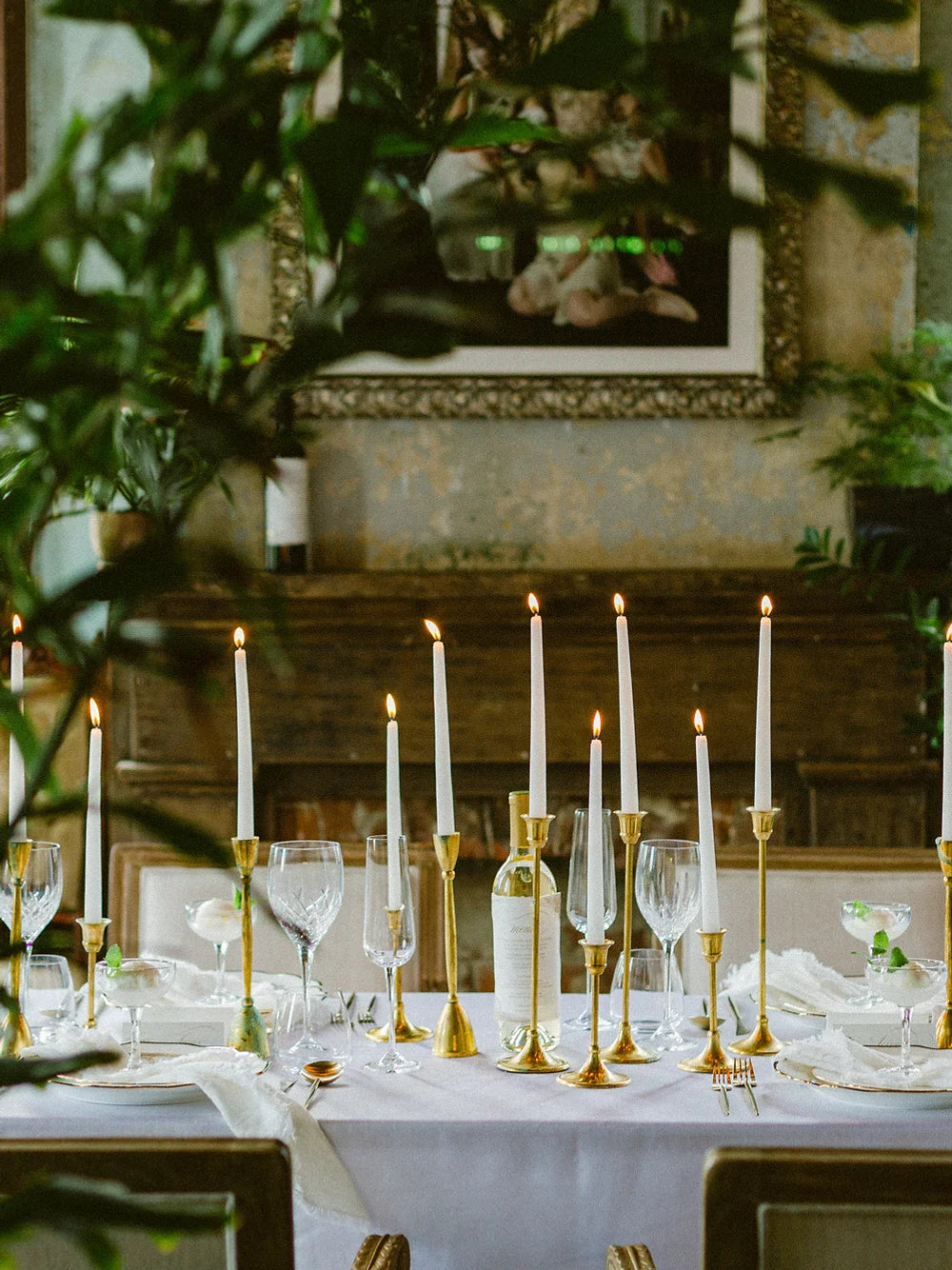 a seated dinner with gold candle stick holders and white taper candles 