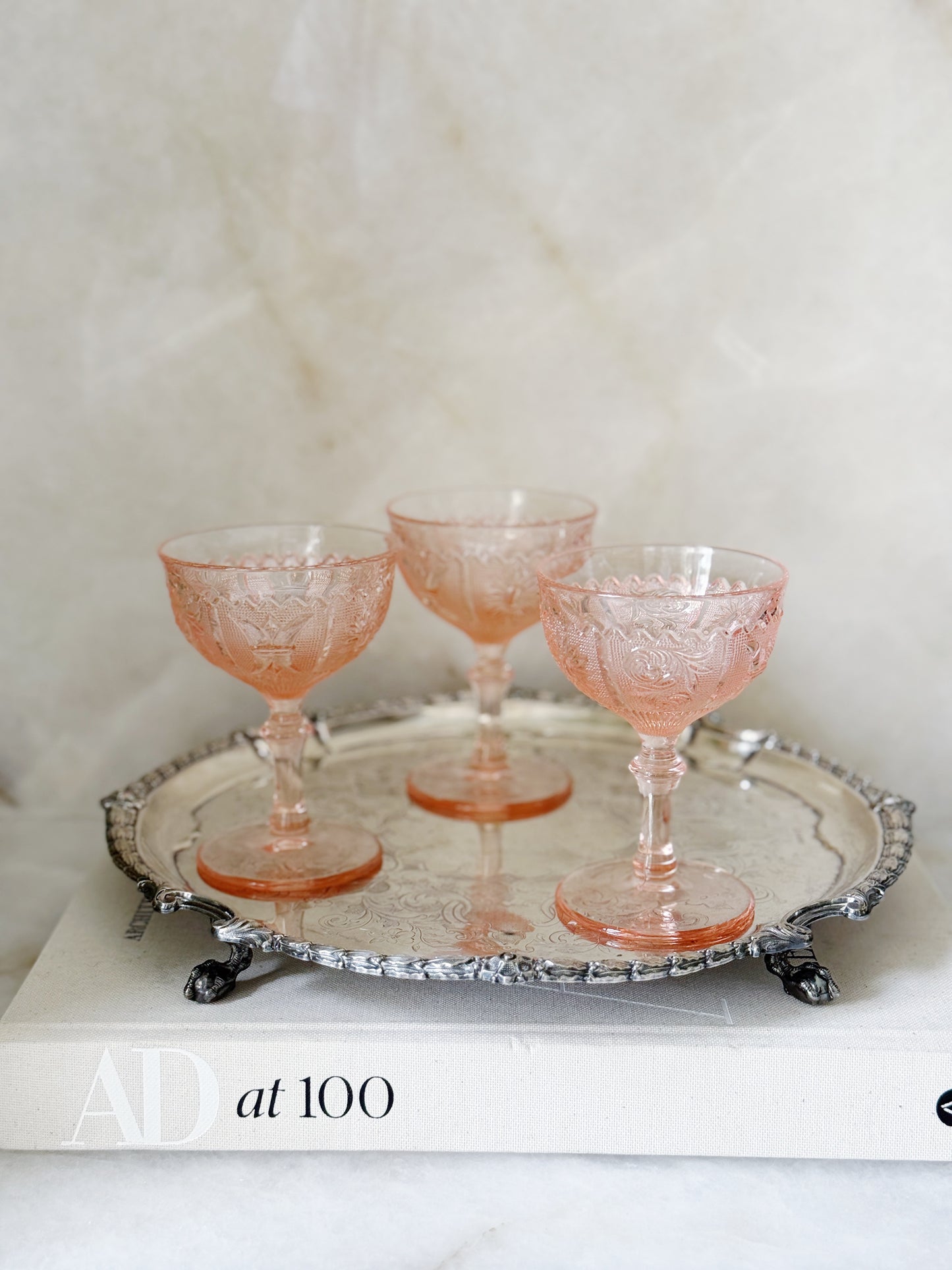 Vintage pink depression glass champagne coupe on an antique serving tray