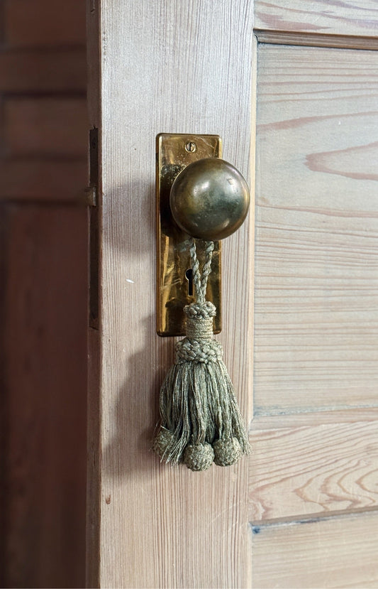 Sage mix decorative tassel hanging on a brass door knob