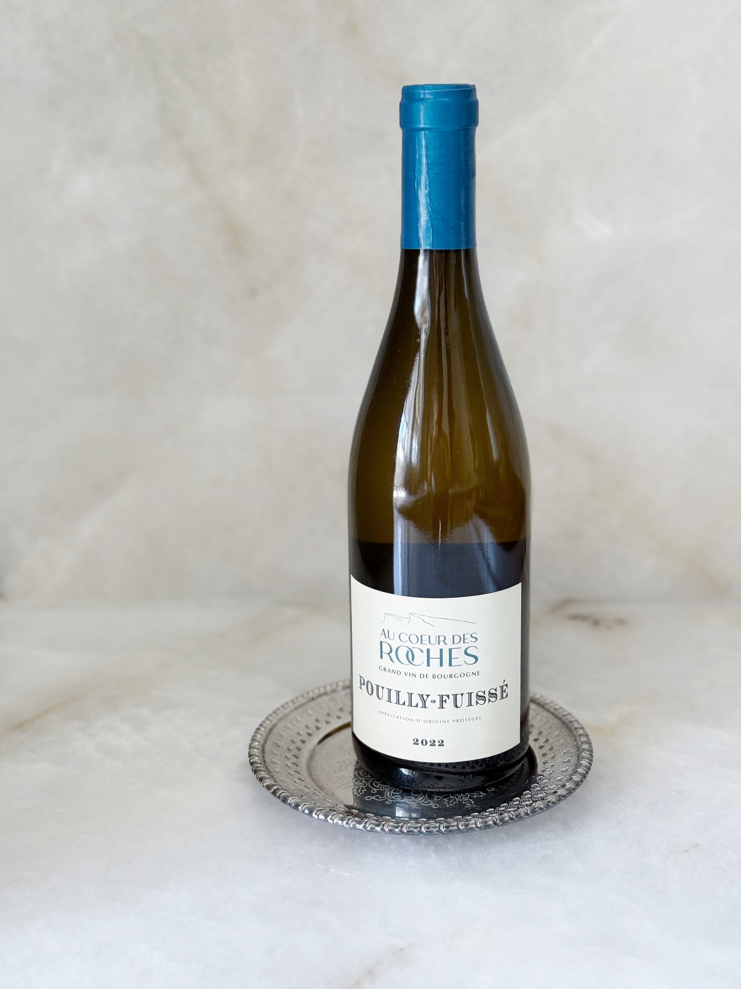 Vintage silver wine coaster and a bottle of puilly fuise