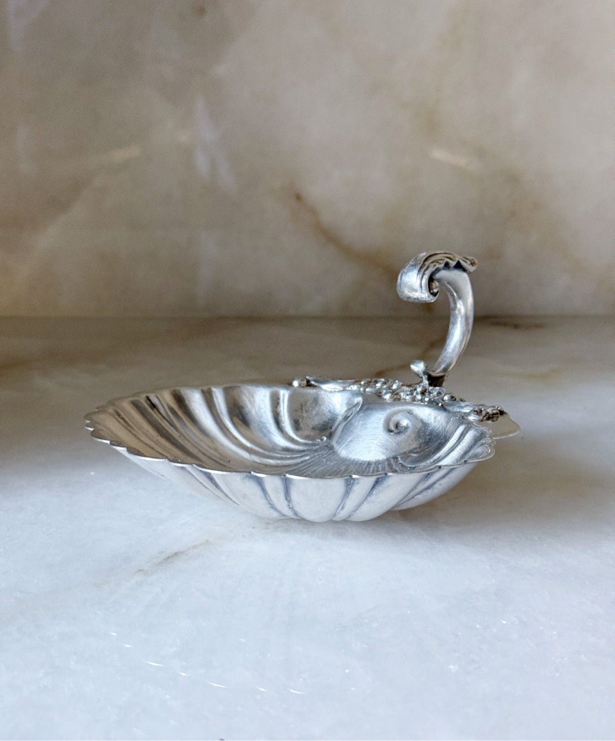 Side view of the vintage silver shell dish showing the curled handle