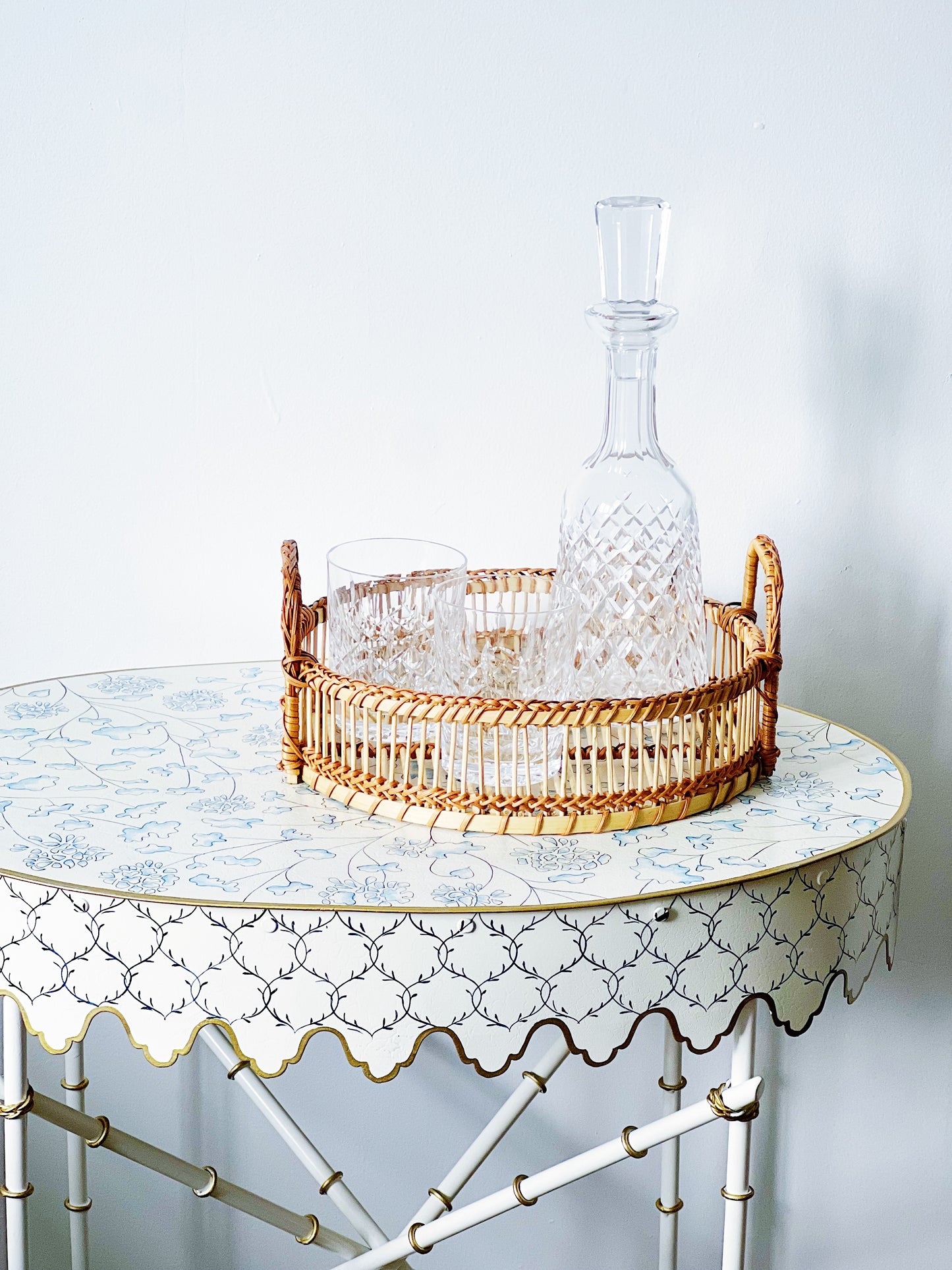 vintage waterford crystal decanter and double old fashioned glasses in a wicker tray on a blue and white tole table 
