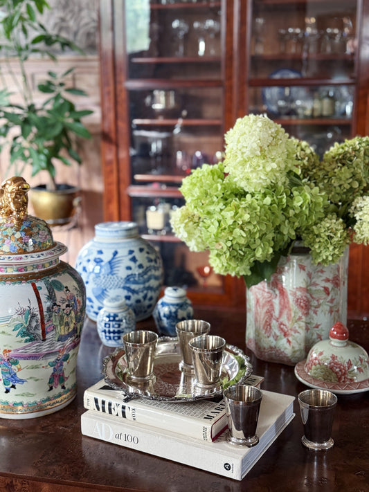 Blue and white ginger jars styled with vintage books, a silver tray, and fresh hydrangeas on a console table.