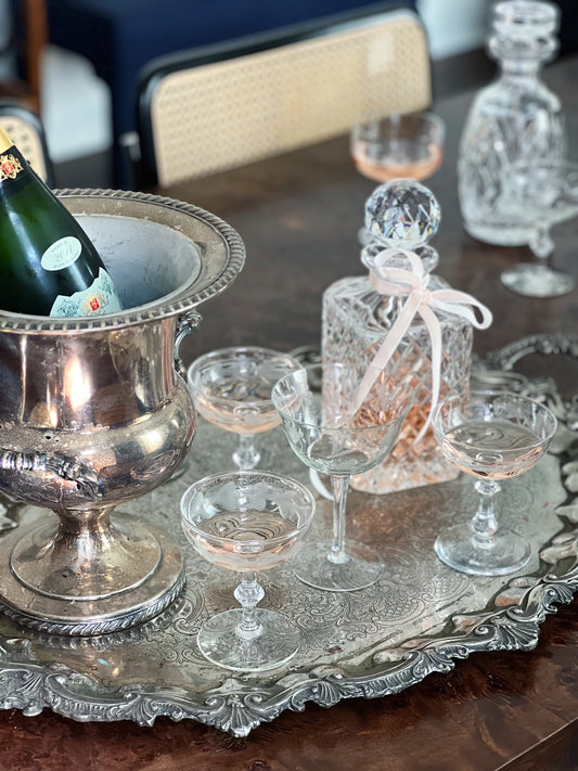 Vintage home bar styled with a silver champagne bucket, crystal decanter, and cocktail glasses