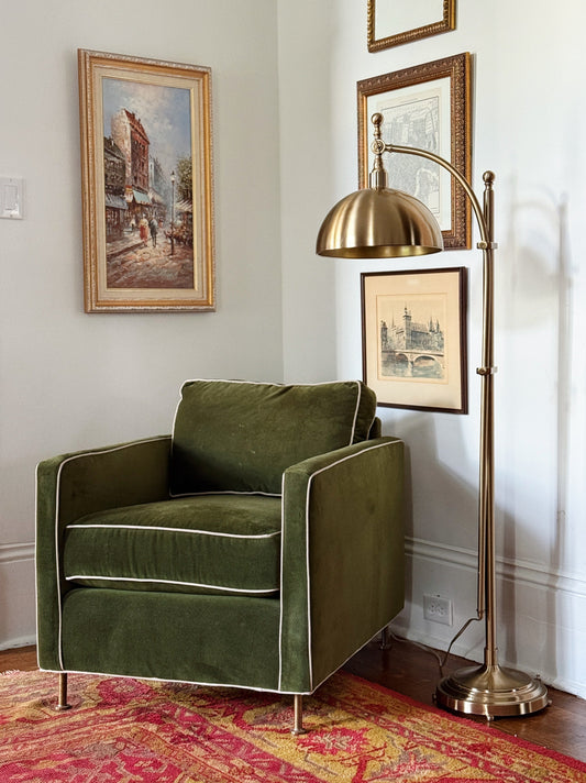 Vintage-inspired living room with layered artwork, brass lighting, and collected furnishings.