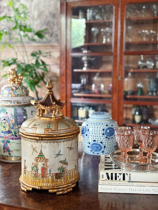 Layered modern vintage vignette featuring a decorative chinoiserie box, blue and white ginger jar, silver tray, crystal stemware, and design books.