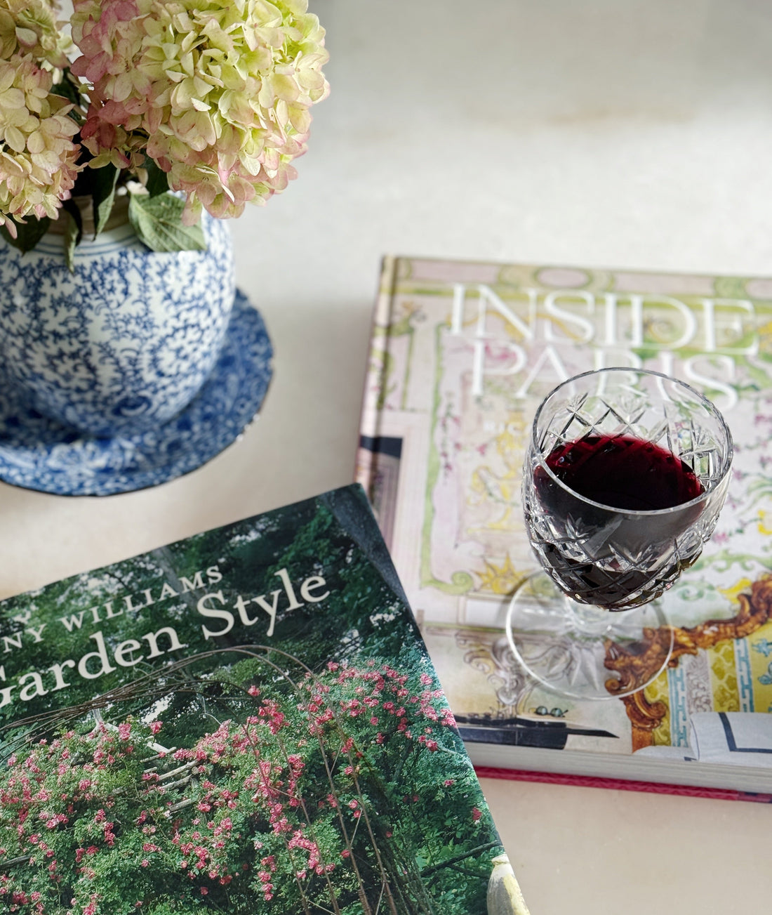 Garden and interior design coffee table books styled with blue and white porcelain and a wine glass