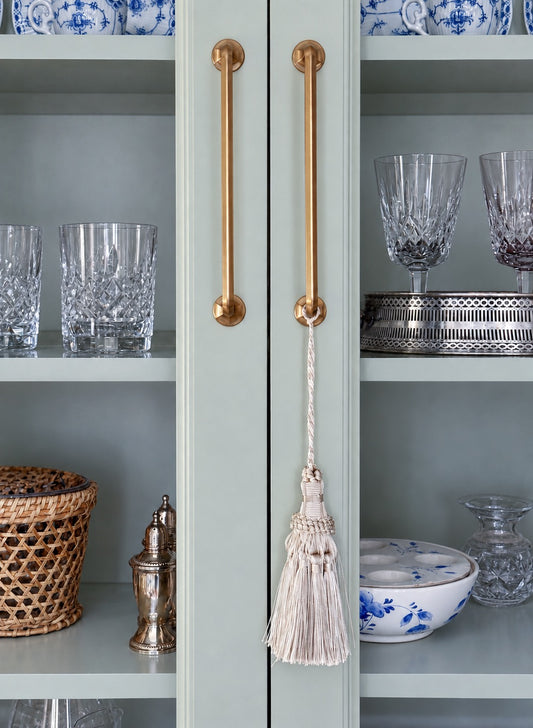 A ivory decorative tassel hanging from a cabinet pull