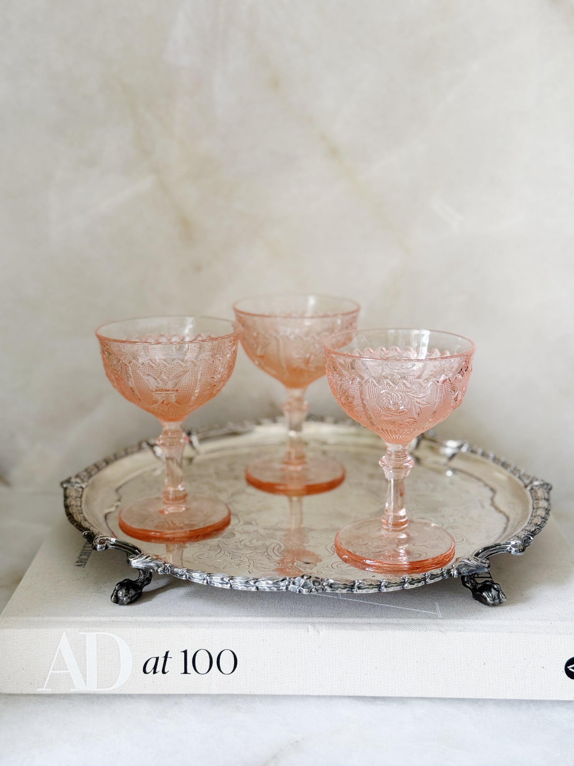 Vintage pink depression glass champagne coupe on an antique serving tray