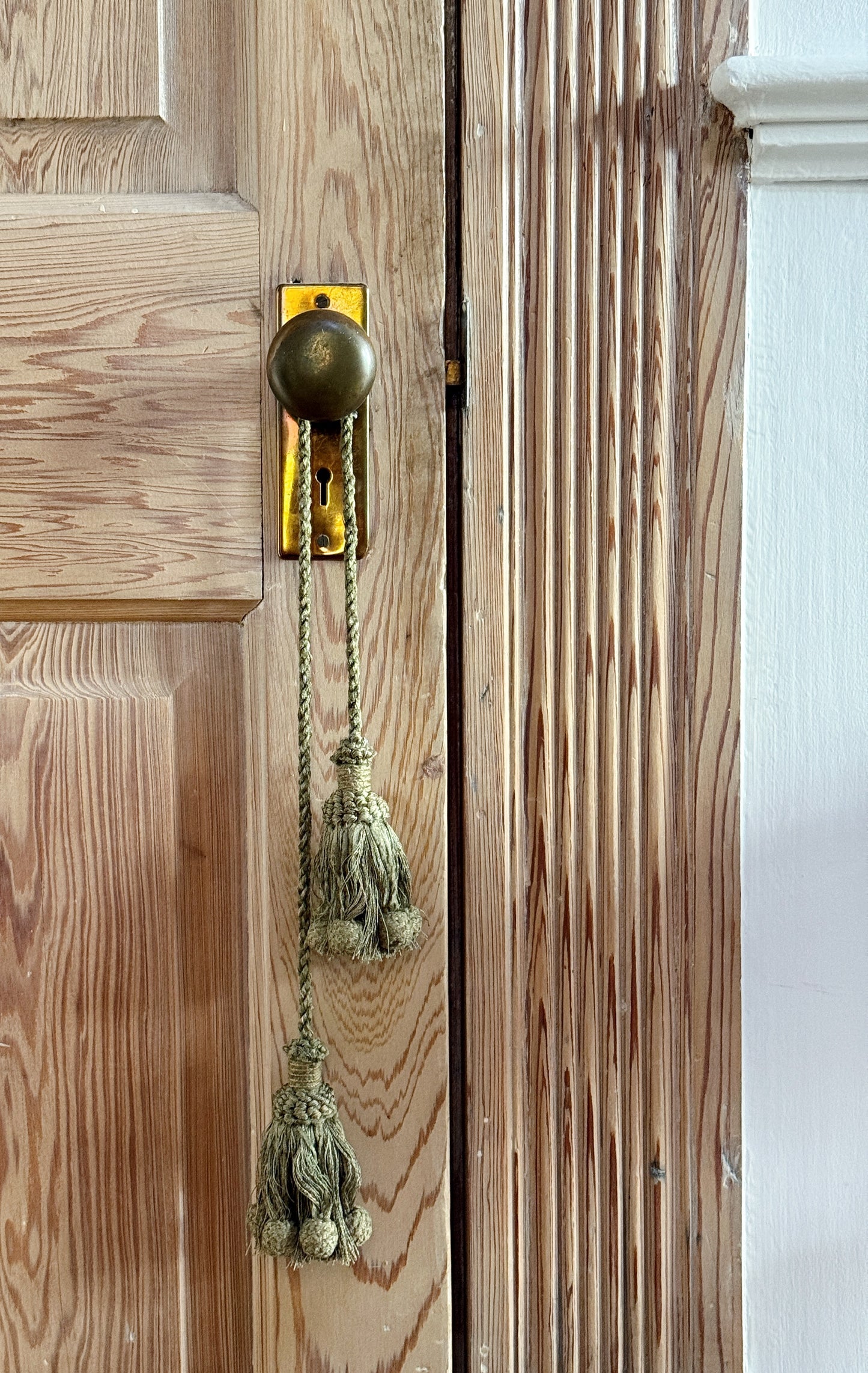 Sage Green Decorative Tassel Tieback on a wooden door with a vintage brass knob