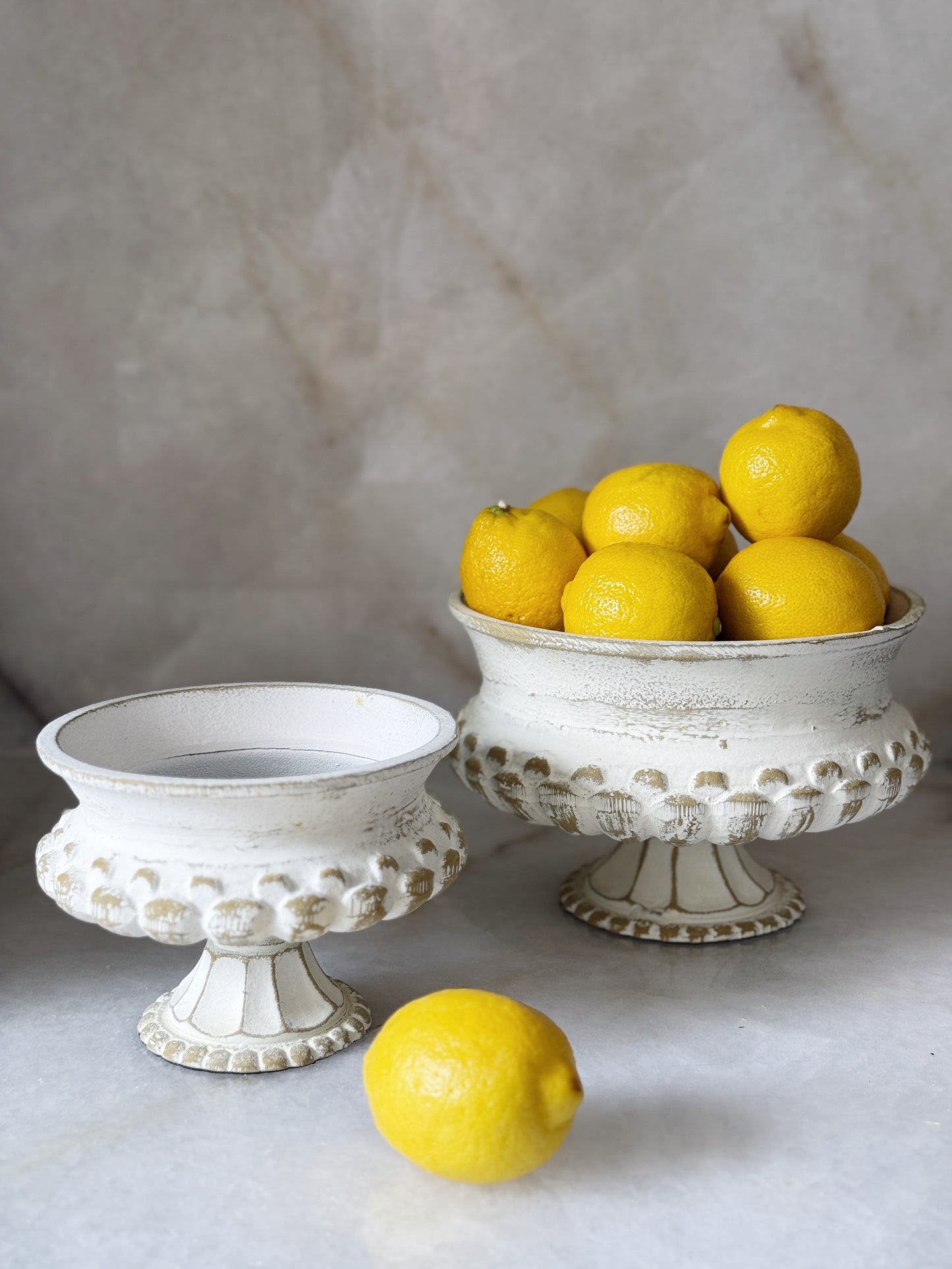 Pedestal urns filled with citrus fruits like lemons 
