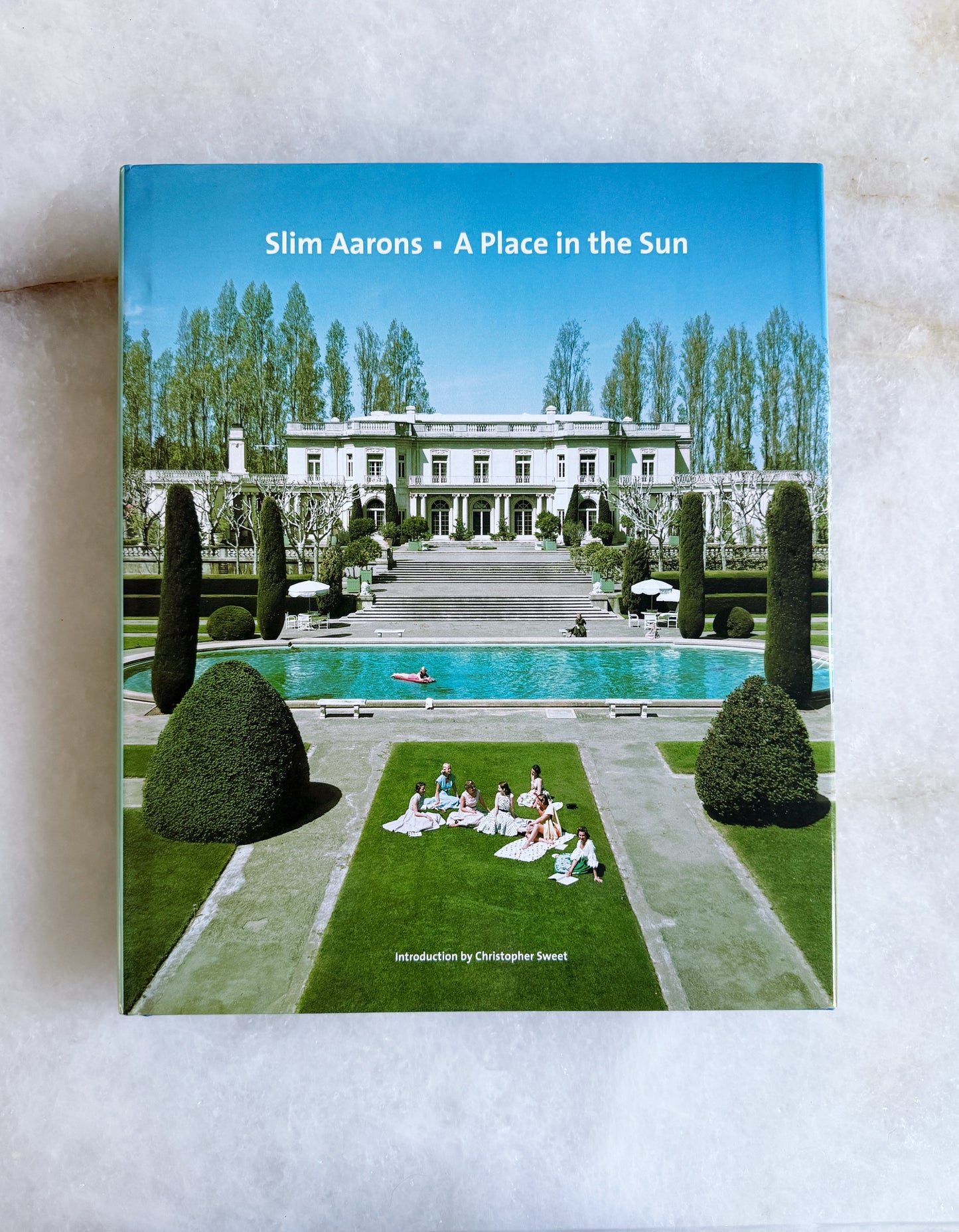 Book cover of 'A Place in the Sun' by Slim Aarons on a marble surface