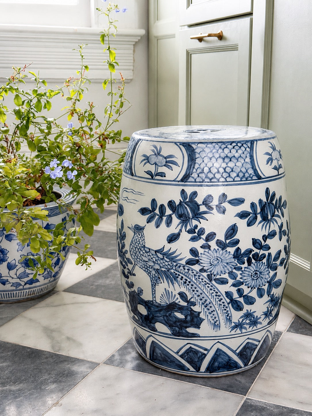 Blue and white Garden seat in a butler pantry with marble floors and sage green cabinets 