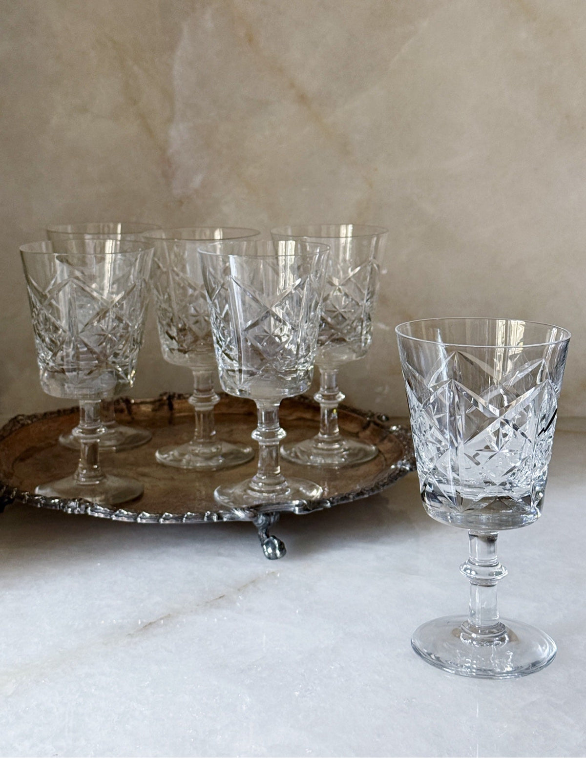 Set of six vintage glass starburst wine goblets styled on a silver tray