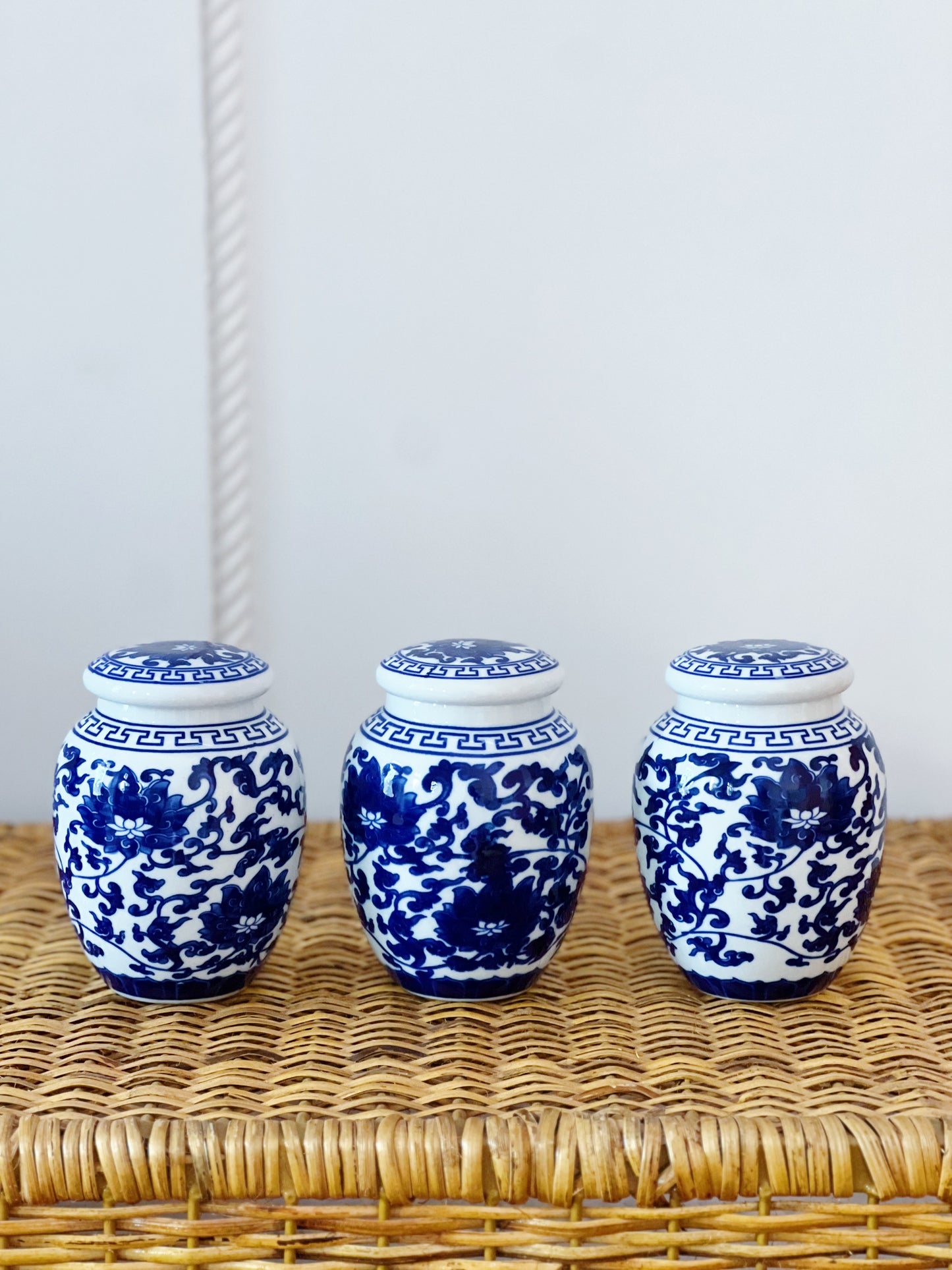 Blue and white willow ware ginger jars on a wicker side table 