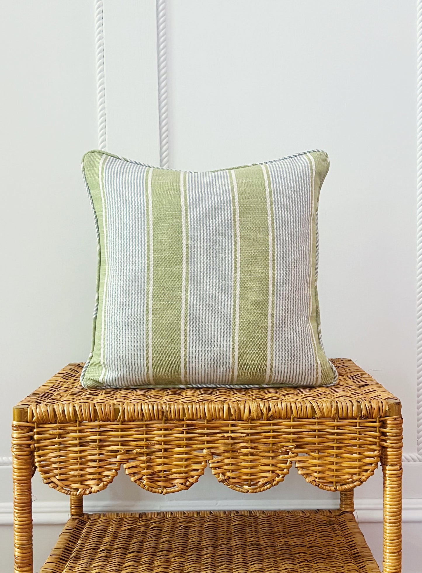 custom pillow in Kravet Barbour stripe in pear on a scalloped wicker side table