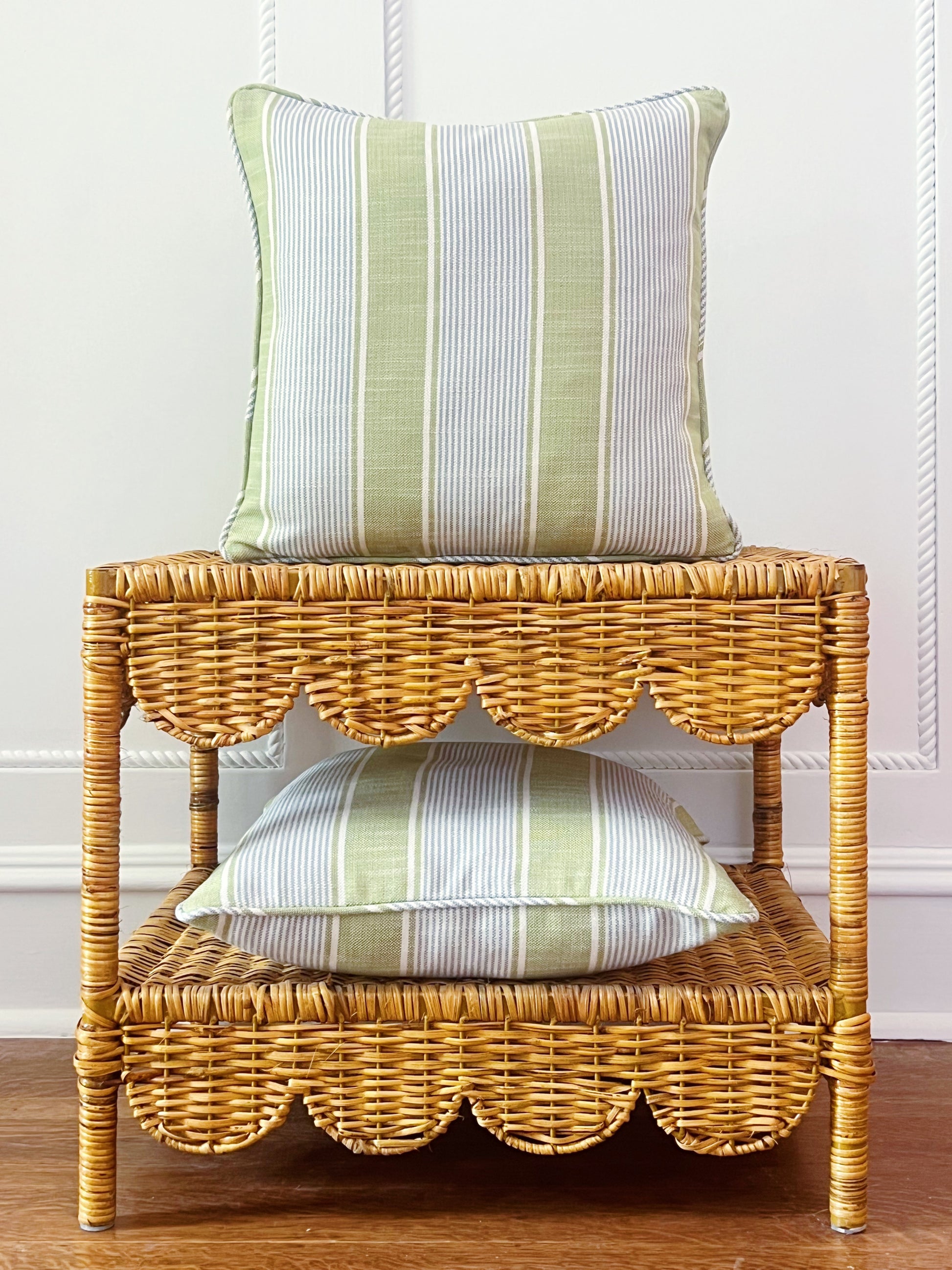 custom pillow in Kravet Barbour stripe in pear on a scalloped wicker side table 