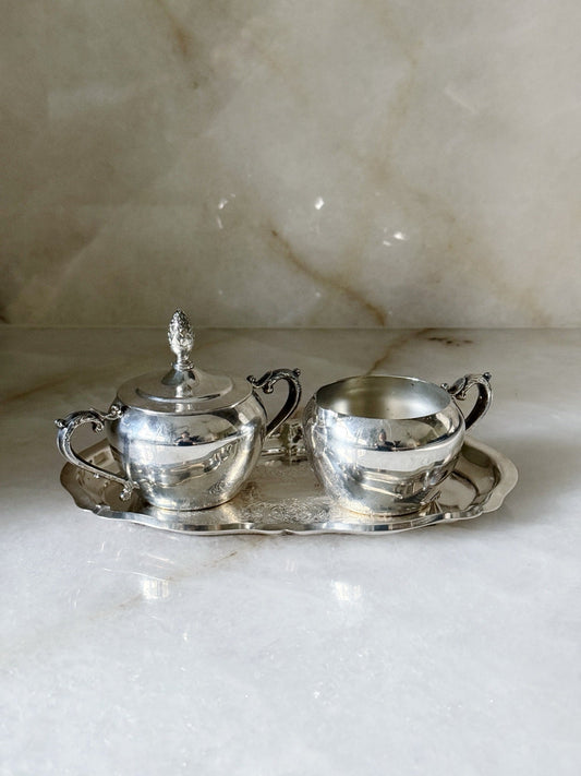 Vintage silverplate sugar and creamer set on an etched silver tray, front view