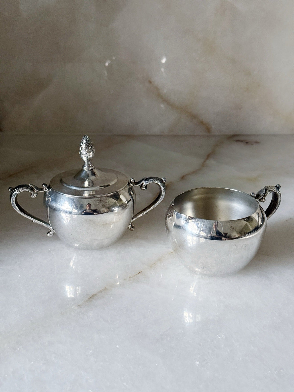Vintage silverplate sugar bowl and creamer beside the etched tray