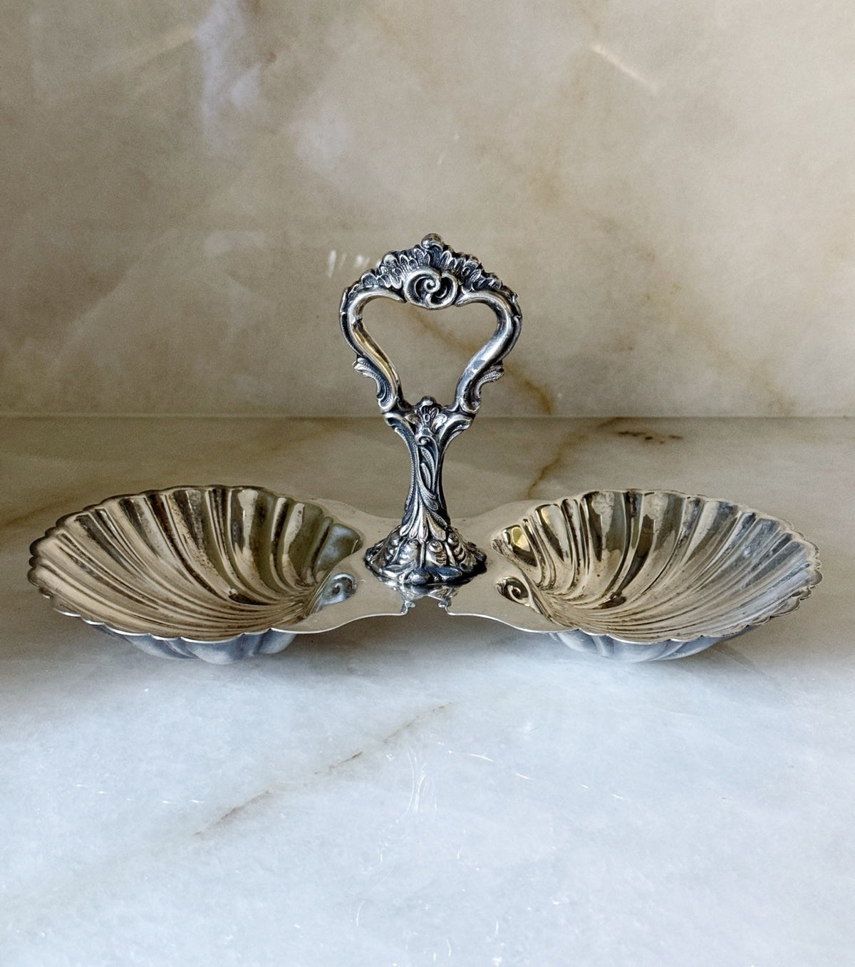 Vintage silver double shell candy dish with ornate scrolling handle, front view