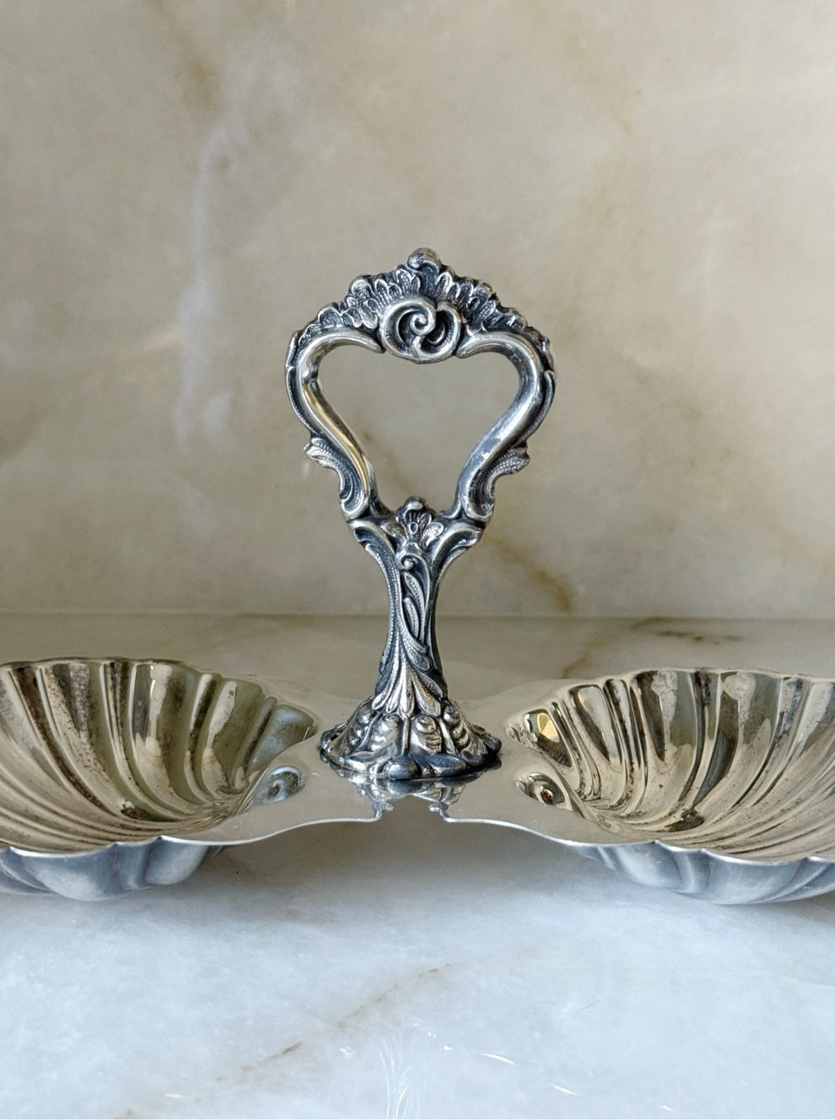 Close-up of the scrolling handle detail on the vintage silver double shell candy dish