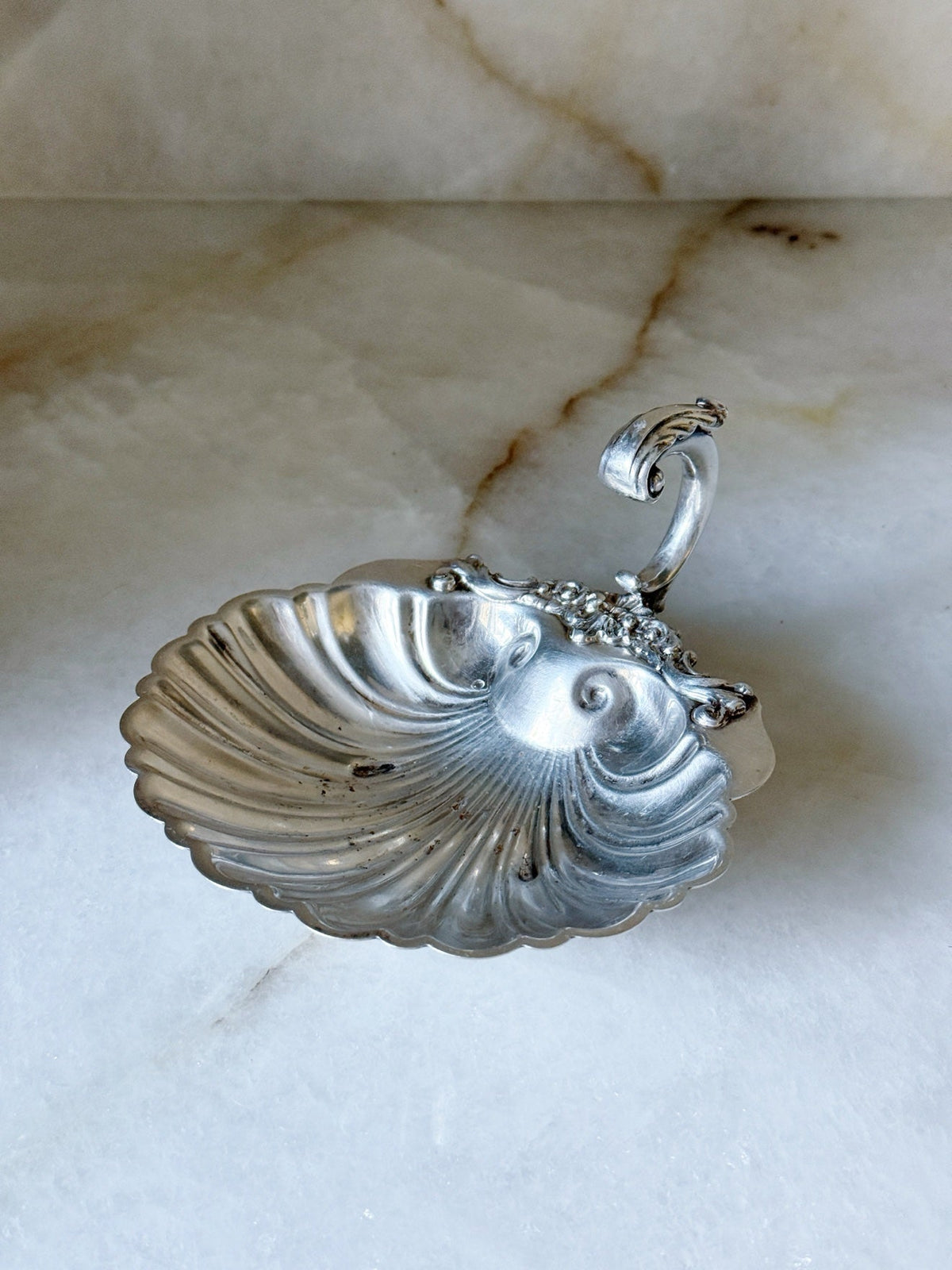 Vintage silver shell dish with ornate floral handle, front view